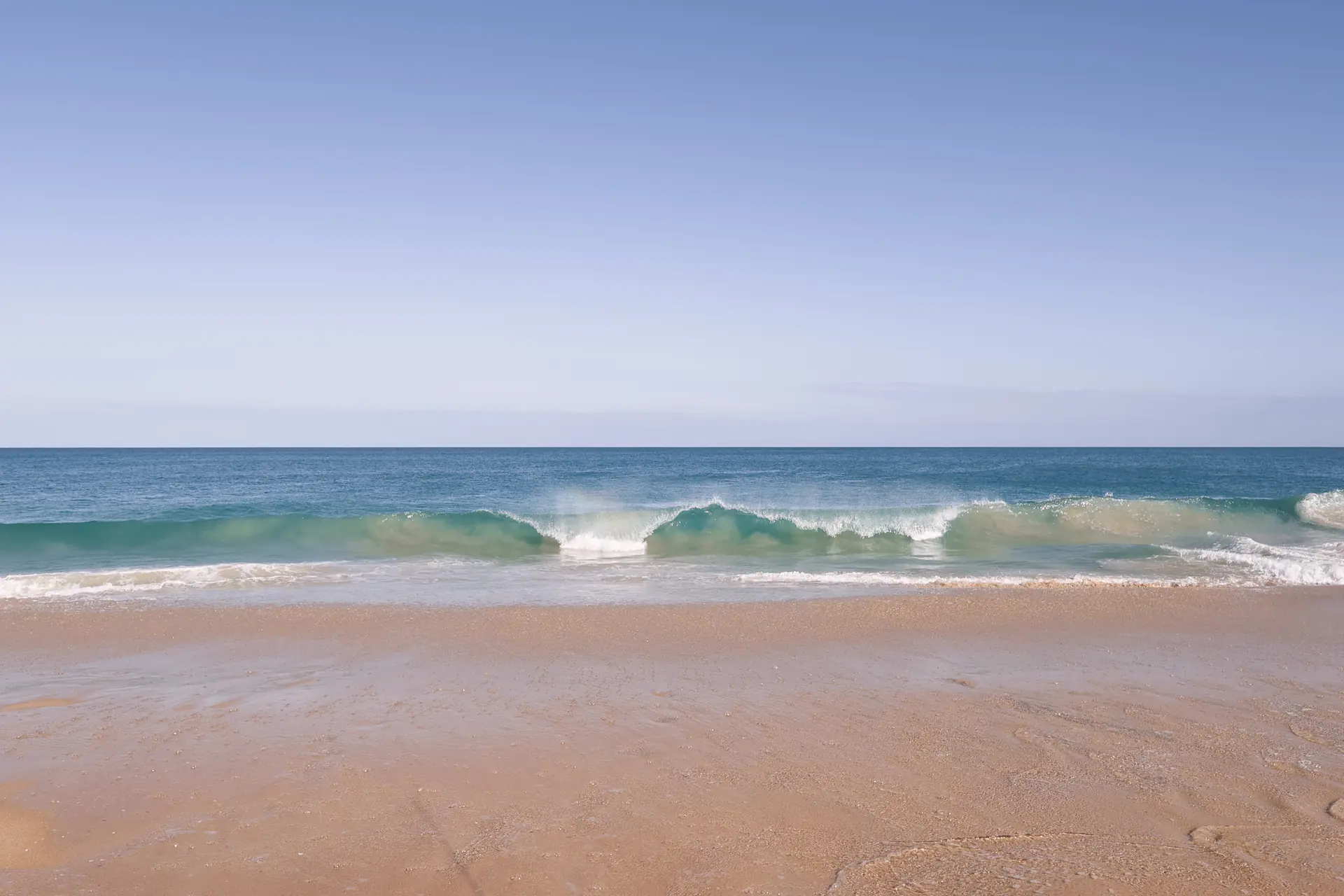 A clean wave breaking on the empty sand at Preston Beach, Western Australia